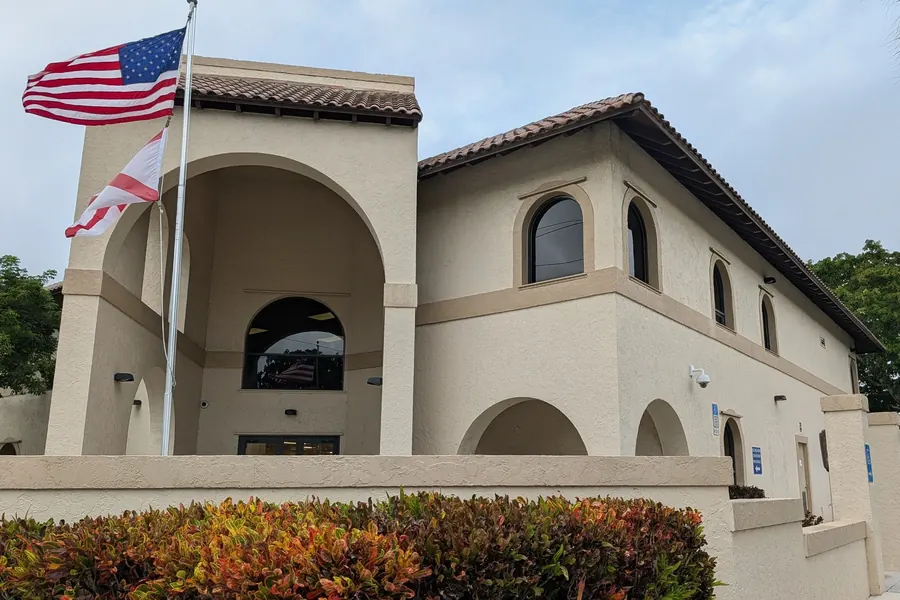 Downtown Boca Raton's old public library building, arched entrance and flags